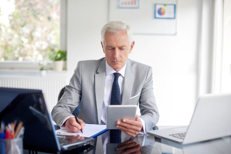 A digitalização é uma das soluções para melhorar a gestão de notas fiscais. Imagem de um executivo trabalhando com a ajuda de um tablet.