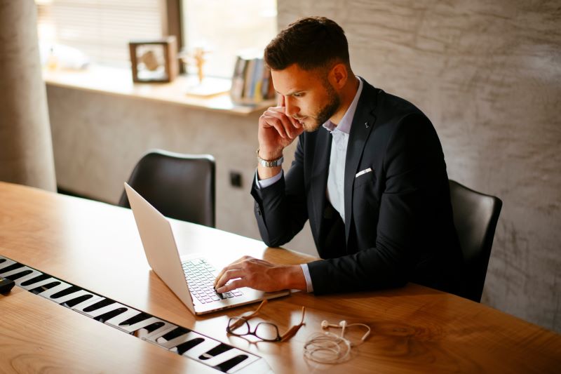 Empresário em seu escritório lendo sobre Ano Calendário em seu computador.